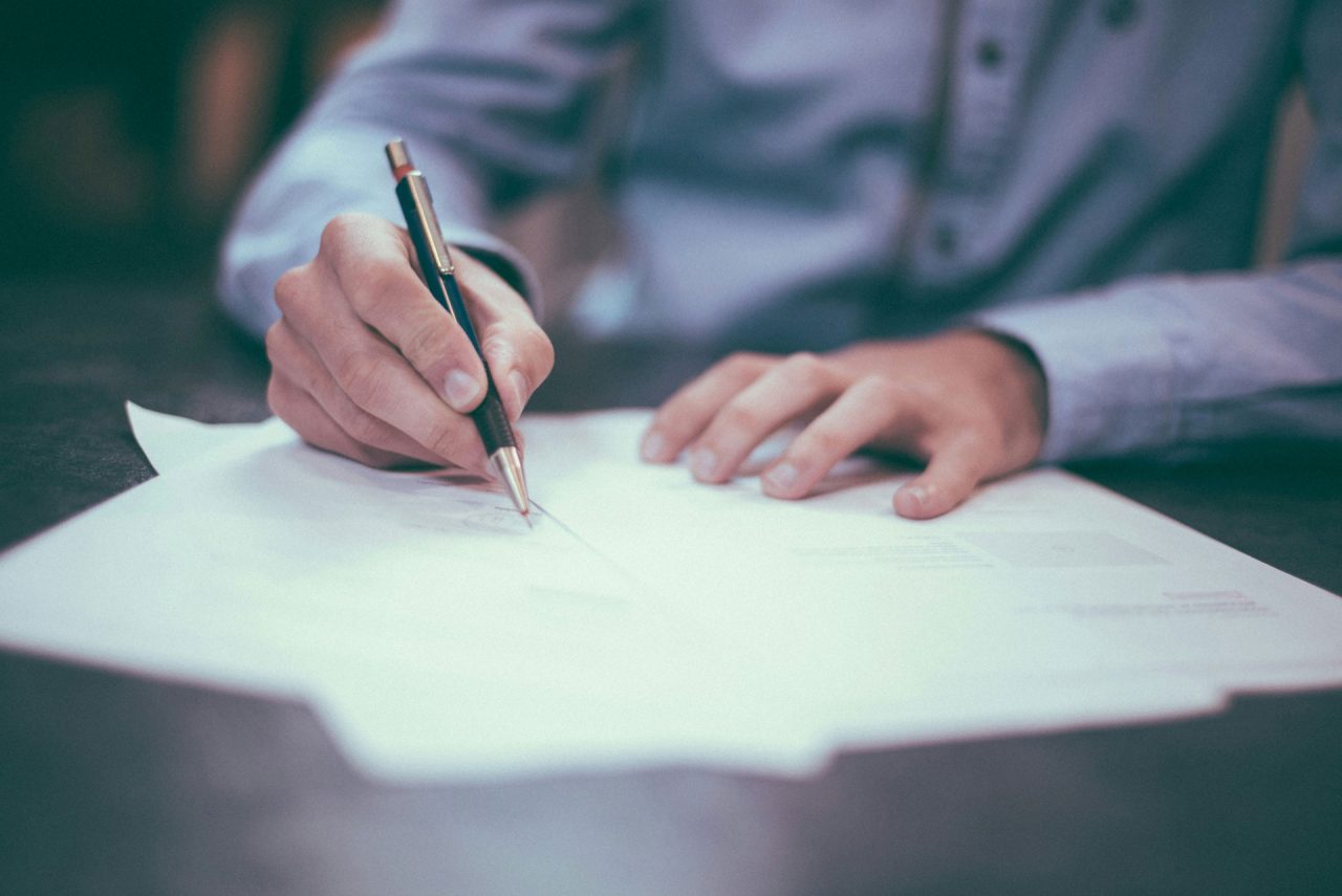 Man in a blue shirt signing a document with a pen — Klea Pharma's launch and distribution agreement in the MEA