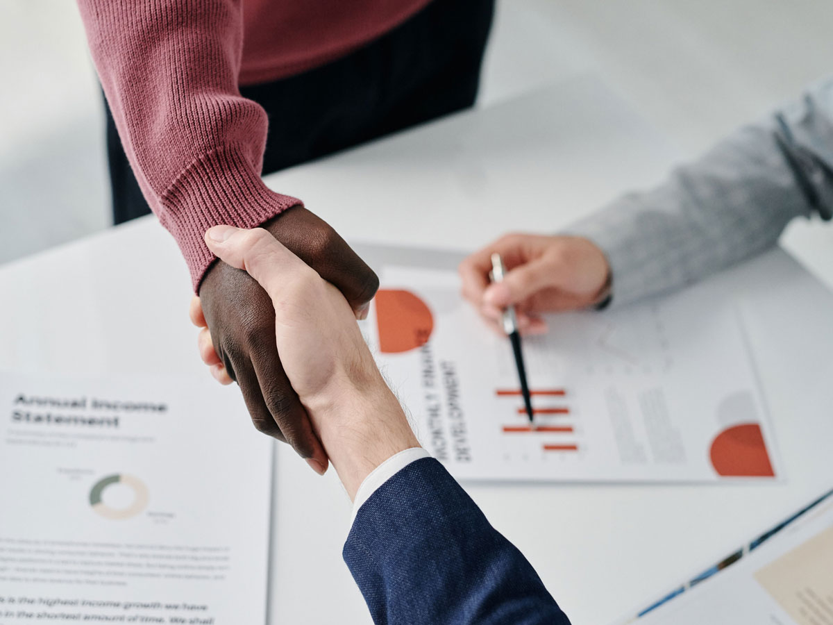 Business partners shaking hands over documents — pharmaceutical licensing partnership with Klea Pharma